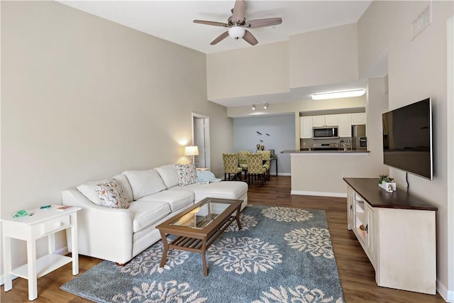 living area with a ceiling fan and dark wood-style flooring