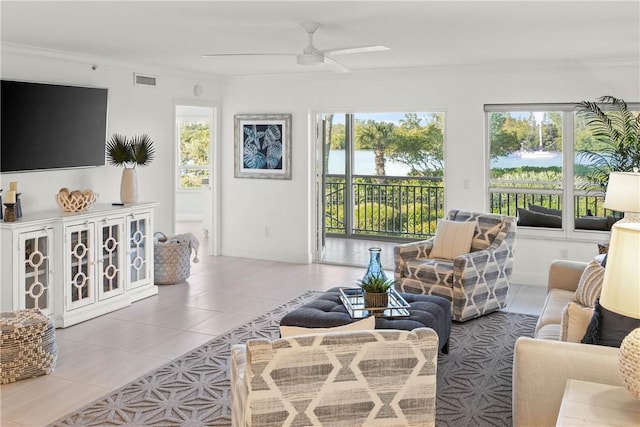 living room featuring ceiling fan, light tile patterned floors, crown molding, and a water view