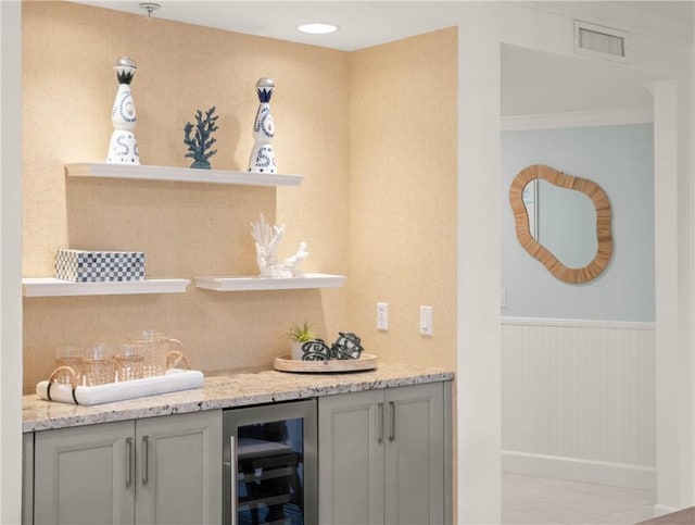 bar with gray cabinetry, beverage cooler, and light stone counters