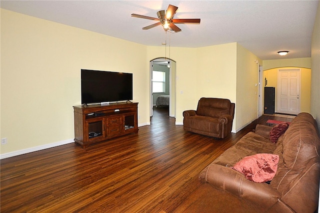 living room with ceiling fan and dark wood-type flooring