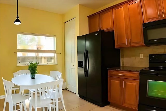 kitchen with tasteful backsplash, black appliances, light tile patterned floors, dark stone countertops, and hanging light fixtures