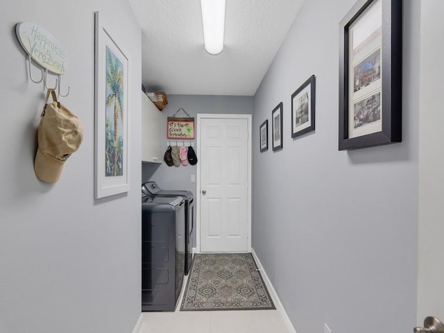 washroom with tile patterned flooring, washing machine and dryer, cabinets, and a textured ceiling