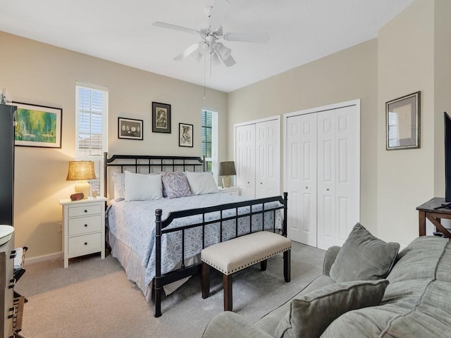 carpeted bedroom featuring multiple windows, two closets, and ceiling fan