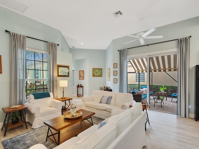 living area featuring a ceiling fan, light wood-type flooring, visible vents, and lofted ceiling