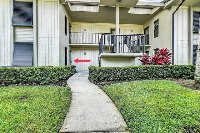 doorway to property with a lawn and a balcony