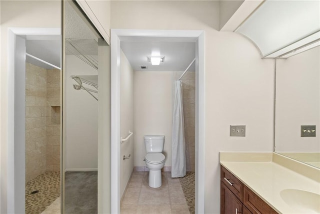 bathroom featuring toilet, tiled shower, tile patterned flooring, and vanity