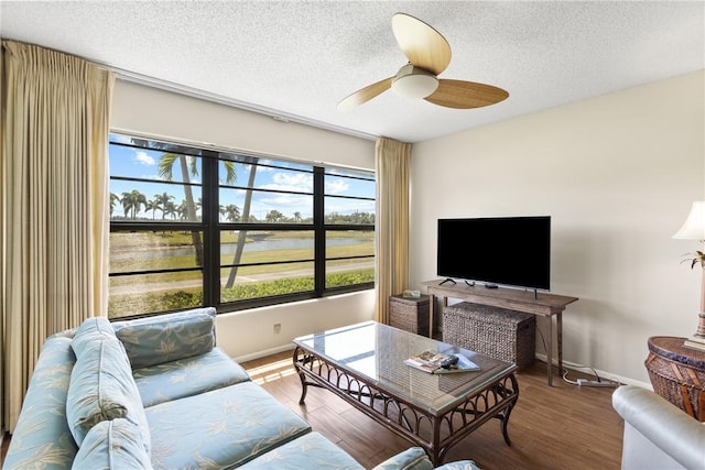 living area with baseboards, a ceiling fan, a textured ceiling, and wood finished floors