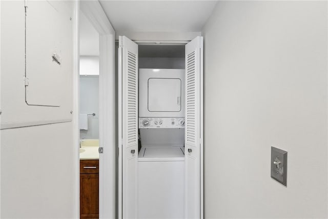 clothes washing area featuring stacked washer and dryer and laundry area