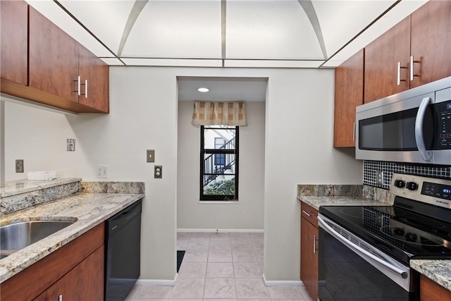 kitchen with baseboards, stainless steel appliances, and light stone counters