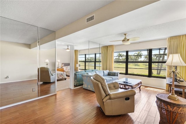 living room with a ceiling fan, a textured ceiling, and visible vents