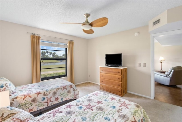 bedroom featuring a ceiling fan, a textured ceiling, visible vents, baseboards, and carpet flooring