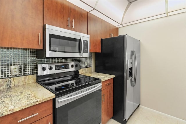 kitchen with decorative backsplash, baseboards, brown cabinets, light tile patterned floors, and stainless steel appliances