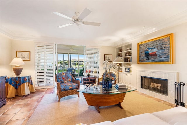 tiled living room with ceiling fan, a tile fireplace, built in features, and crown molding