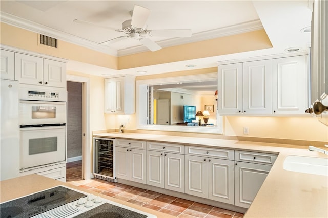 kitchen with ornamental molding, white cabinets, beverage cooler, white appliances, and ceiling fan