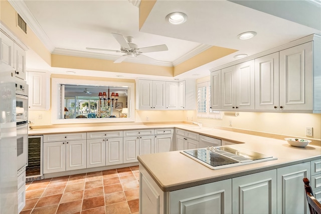 kitchen with kitchen peninsula, white cabinetry, black electric stovetop, and crown molding