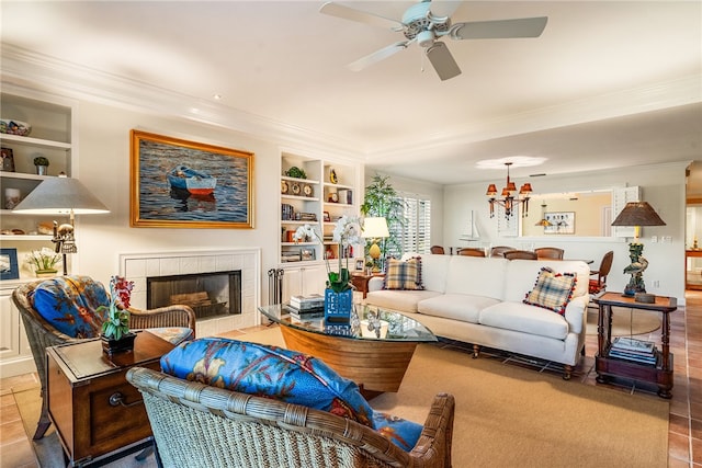 living room featuring a tiled fireplace, light tile patterned floors, ceiling fan with notable chandelier, and ornamental molding