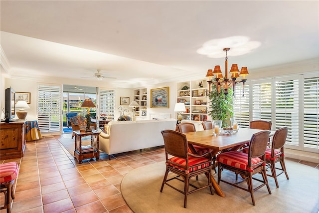 tiled dining space with ceiling fan with notable chandelier, built in shelves, and ornamental molding