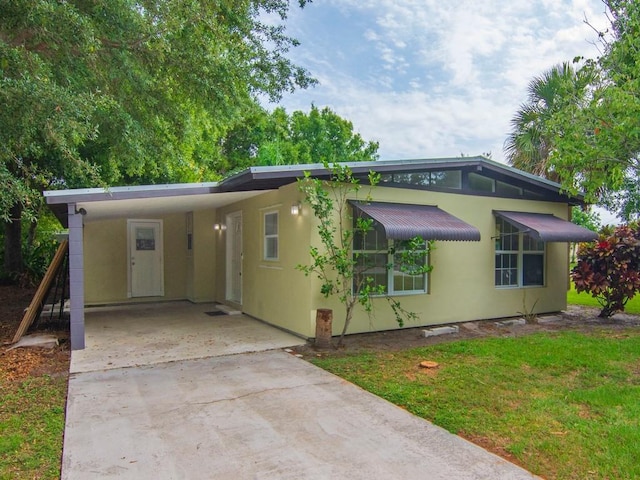 660 14th St, Vero Beach, FL 32960 - mid-century inspired home featuring driveway, an attached carport, stucco siding, and a front lawn