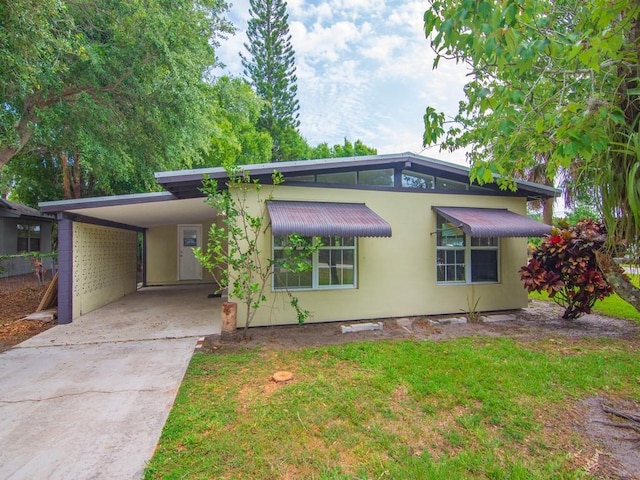 660 14th St, Vero Beach, FL 32960 - mid-century home featuring driveway, an attached carport, and a front lawn