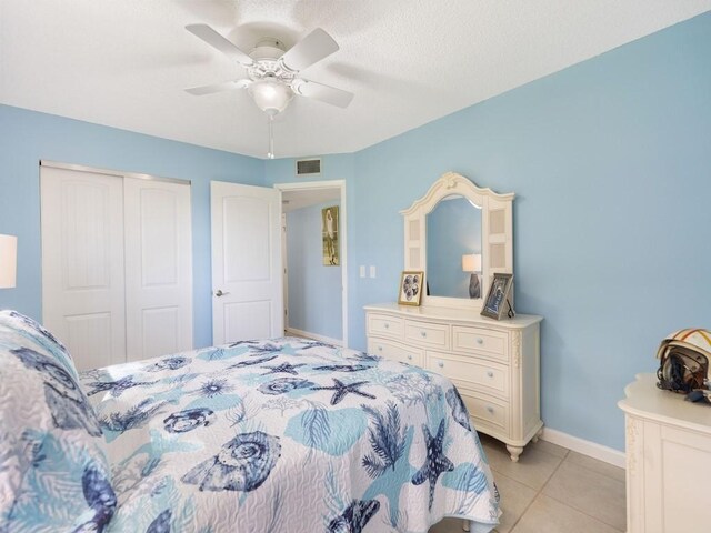 tiled bedroom with a closet, a textured ceiling, and ceiling fan