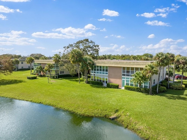 back of property featuring a water view and a lawn