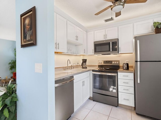 kitchen featuring light tile patterned floors, ceiling fan, appliances with stainless steel finishes, white cabinets, and sink