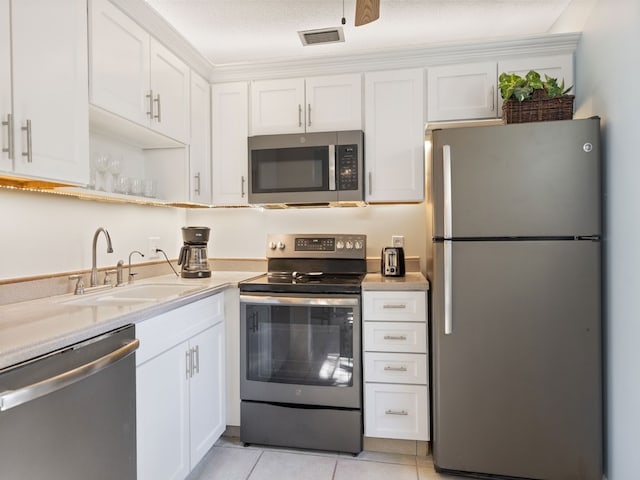 kitchen featuring stainless steel appliances, sink, a textured ceiling, light tile patterned floors, and white cabinets