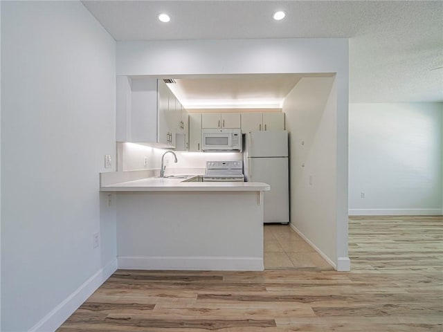 2800 Indian River Blvd Unit L2, Vero Beach, FL 32960 - kitchen with white appliances, a sink, a peninsula, light wood-style floors, and light countertops