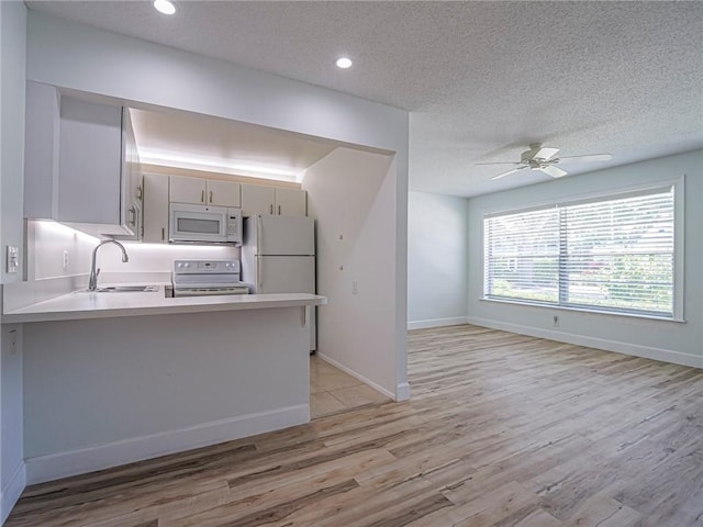 2800 Indian River Blvd Unit L2, Vero Beach, FL 32960 - kitchen featuring white appliances, a sink, a peninsula, light wood finished floors, and a textured ceiling