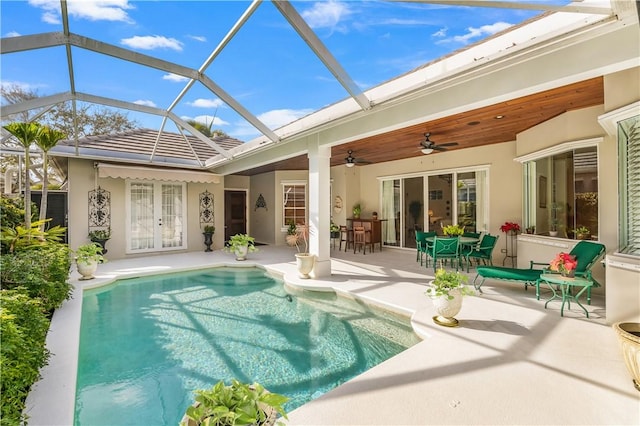 pool with french doors, a patio area, a lanai, and a ceiling fan