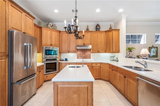 kitchen featuring a sink, hanging light fixtures, light countertops, appliances with stainless steel finishes, and an island with sink