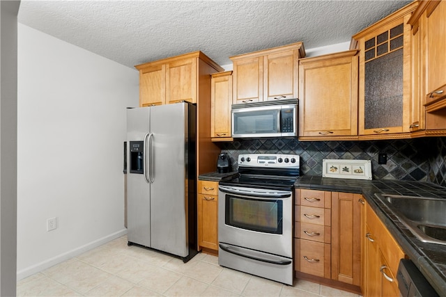 kitchen with stainless steel appliances, sink, backsplash, and light tile patterned floors