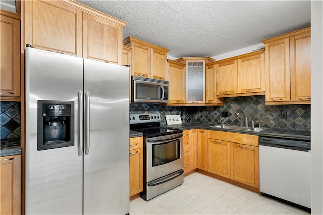 kitchen with appliances with stainless steel finishes, a textured ceiling, light tile patterned floors, decorative backsplash, and sink