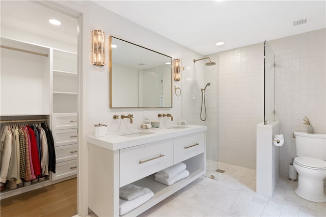 bathroom with tiled shower, tile walls, vanity, and toilet