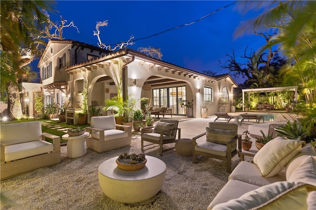 patio at night with outdoor lounge area and a balcony