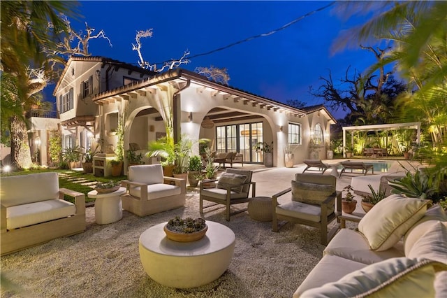 601 Flamevine Ln, Vero Beach, FL 32963 - back of house at twilight featuring an outdoor living space, a patio, stucco siding, an outdoor pool, and french doors