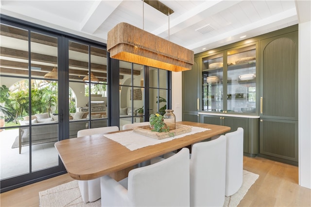 dining space with beamed ceiling and light hardwood / wood-style flooring