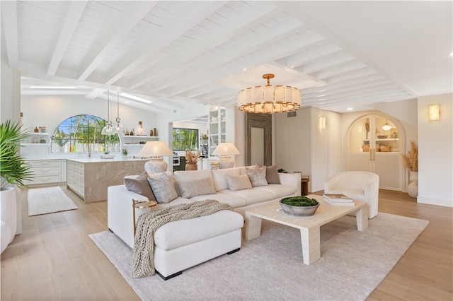 living room featuring light hardwood / wood-style floors, an inviting chandelier, and vaulted ceiling with beams