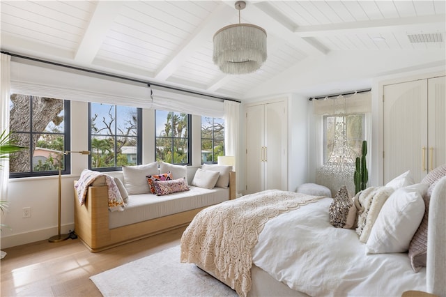 bedroom with light wood-type flooring, multiple windows, and vaulted ceiling with beams