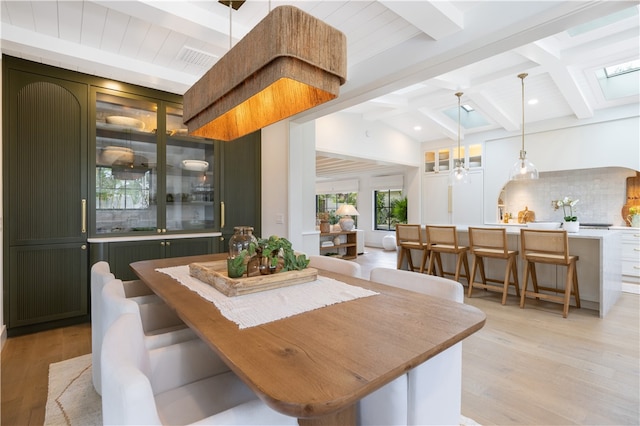 dining space with light wood-type flooring, vaulted ceiling with beams, and ceiling fan