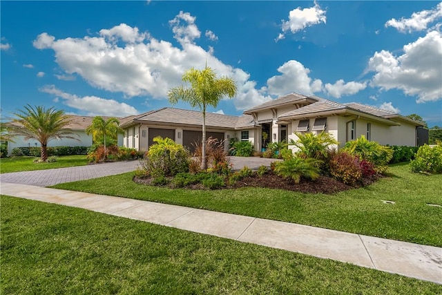 ranch-style house featuring a garage, driveway, a front lawn, stucco siding, and a tiled roof