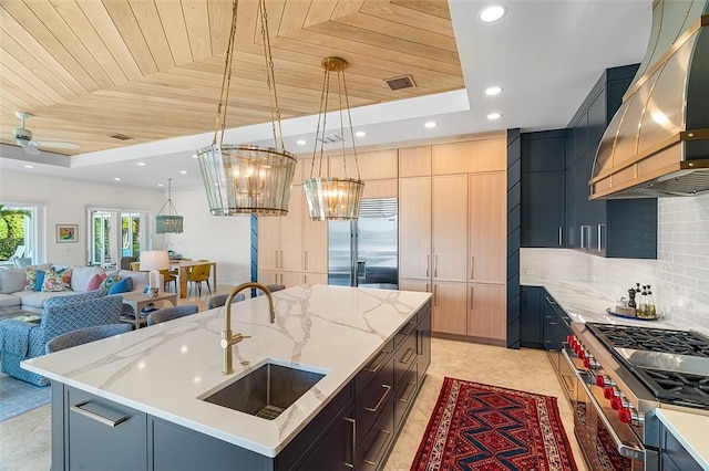 815 Starboard Dr, Vero Beach, FL 32963 - kitchen with wall chimney exhaust hood, sink, a center island with sink, premium appliances, and a raised ceiling
