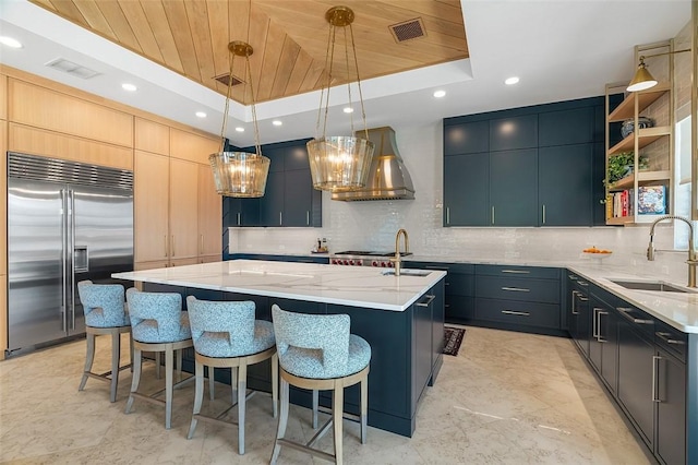 815 Starboard Dr, Vero Beach, FL 32963 - kitchen with sink, built in refrigerator, hanging light fixtures, a raised ceiling, and a center island with sink