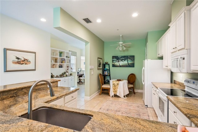 kitchen featuring visible vents, light stone counters, white appliances, a ceiling fan, and a sink