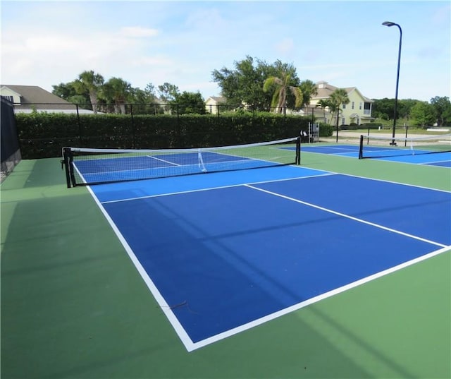 view of tennis court featuring community basketball court and fence