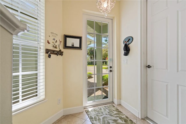 doorway featuring light tile patterned flooring, a notable chandelier, and baseboards