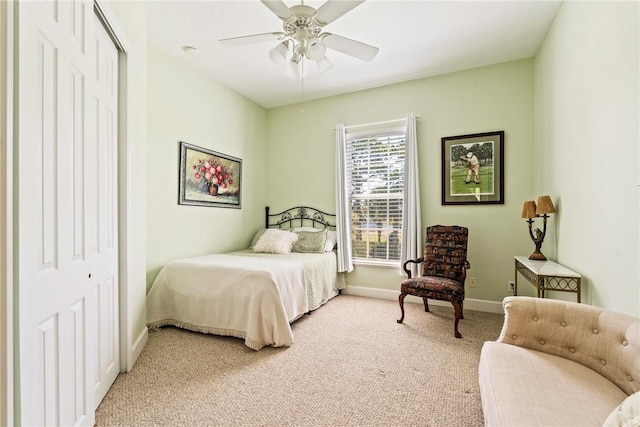 bedroom featuring light carpet, ceiling fan, a closet, and baseboards