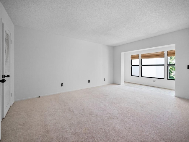 spare room featuring light carpet and a textured ceiling