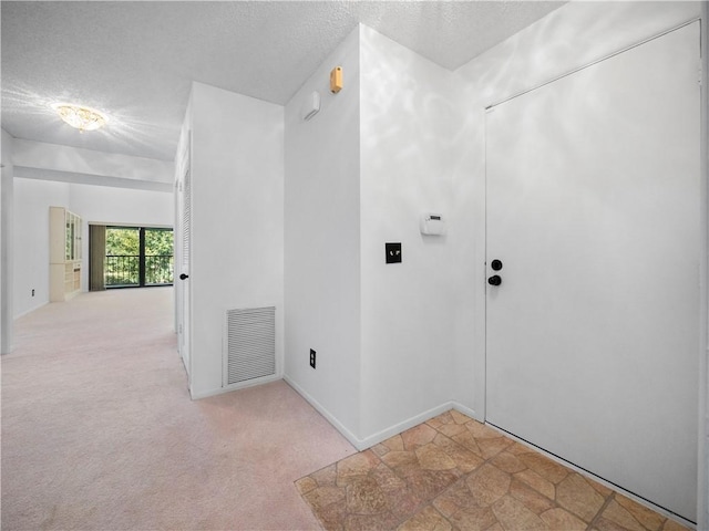 hall featuring light carpet and a textured ceiling