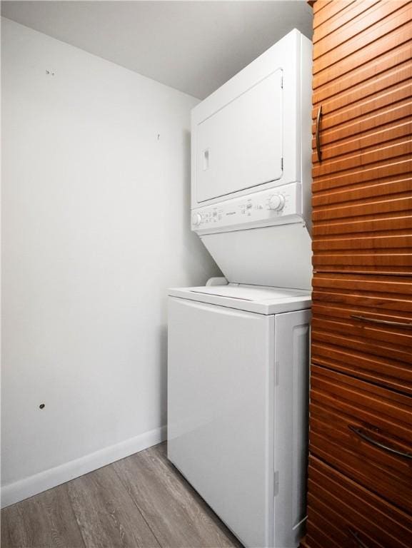 washroom featuring hardwood / wood-style floors and stacked washing maching and dryer